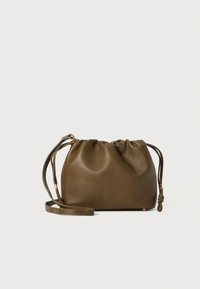 Τσαντάκι από δέρμα ελιάς με εφέ σούρας, λεία υφή, ρυθμιζόμενο λουράκι και διακοσμητικό κόμπο. Μαλακό, στρογγυλεμένο σχήμα με ελάχιστα μεταλλικά στοιχεία.