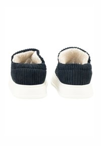 Zapatos de ante azul marino tipo slip-on con un suave forro de felpa color crema y una suela de goma blanca. Se puede ver una textura acanalada en la parte superior.