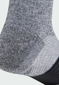 Calcetines de lana gris con un patrón texturizado, que presentan un talón y una punta oscuros, y un diseño de canalé más claro cerca del puño.