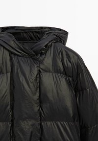 Černá péřová bunda s lesklou, texturovanou tkaninou, vybavená kapucí a patentkami. Prošívaný design s viditelnými švy.