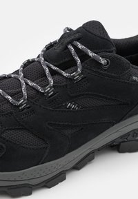 Scarpa da trekking nera caratterizzata da una combinazione di materiali scamosciati e mesh, suola in gomma spessa e lacci grigi con un motivo testurizzato.