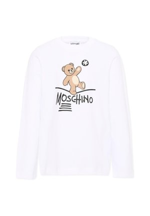 Biała koszula z długim rękawem z grafiką misia bawiącego się czarno-białą piłką nad napisem Moschino czarnymi literami.