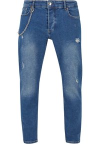 Vaqueros de mezclilla azul con corte ajustado, que presentan un accesorio de cadena, detalles desgastados y un sutil desvanecimiento para añadir textura.