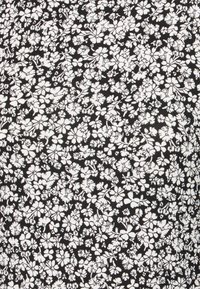 Blommönstrad tyg med små vita blommor och blad på en svart bakgrund. Texturen verkar slät med ett mönstrat design genom hela.