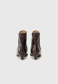 Bottines en cuir marron avec un motif crocodile, dotées d'un petit talon et d'une sangle à l'arrière pour un enfilage facile.