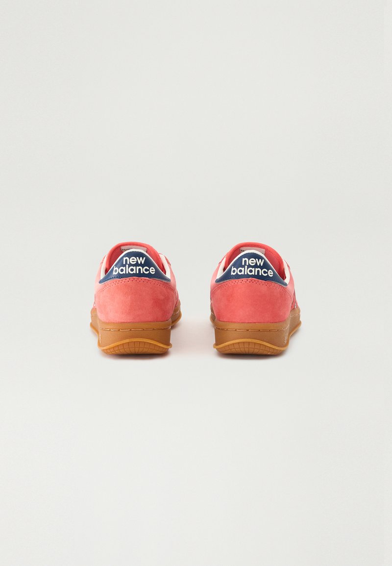 Zapatillas de ante rojas con acentos blancos y un logo en azul marino. Presentan una suela de goma y una silueta clásica de corte bajo.