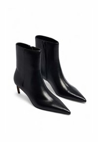 Črne usnjene gležnjarje s špicastim nosom, vitko silhueto in stranskim zadrgo. Imajo tanek, visok peto za dodatno višino.