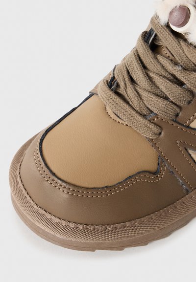 Brauner Lederstiefel mit strukturiertem Stoffdetail, runder Spitze, gestickten Akzenten und braunen Schnürsenkeln. Mit einem Kunstfellkragen und Gummisohle.