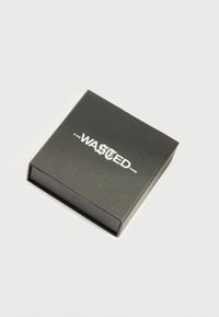 Μαύρο ορθογώνιο κουτί με λευκό κείμενο "WASTED Paris" σε μικτούς γραμματοσειρές στο καπάκι, τοποθετημένο σε απλό λευκό φόντο.