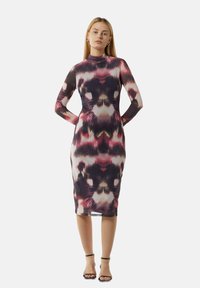 Figurbetontes, langärmliges Kleid aus glattem Stoff, das ein gewagtes abstraktes Muster mit dunklen und kräftigen Farben zeigt. Mittlere Wadenlänge.