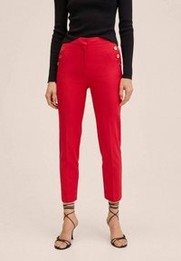 Pantalon rouge ajusté à taille haute, avec des accents décoratifs de boutons dorés sur les côtés. Tissu lisse avec une longueur jusqu'à la cheville, coupée sur mesure.