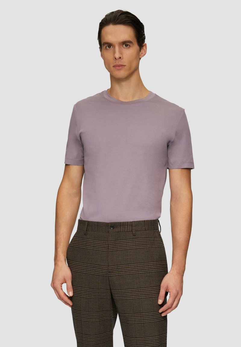 Licht lavendelkleurig t-shirt met korte mouwen in een gladde stof, gecombineerd met bruine geplooide pantalon met een subtiel ruitpatroon.