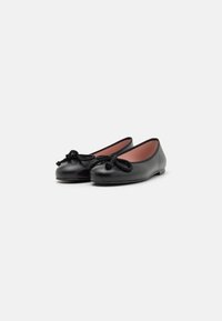 Bailarinas de cuero negro con punta redondeada, que presentan un detalle de cuerda anudada en la parte delantera y un acabado suave y ligeramente brillante.