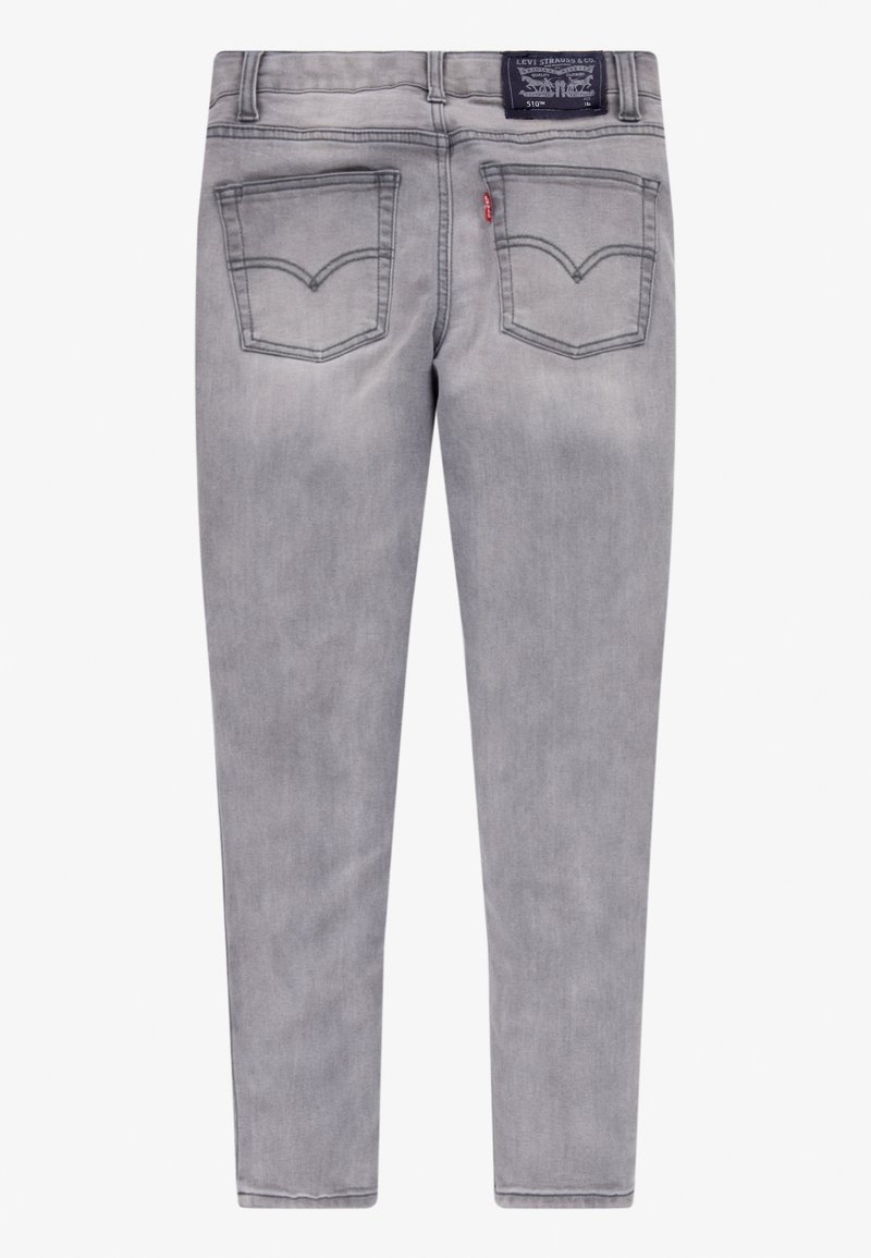 Jeans de mezclilla gris con un ajuste slim, que cuentan con dos bolsillos traseros con un patrón de costura y una etiqueta en la cinturilla.