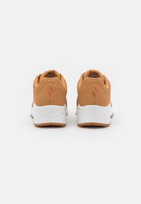 Beige Sneaker mit einem glatten Leder-Obermaterial, weißer Zwischensohle und brauner Gummi-Außensohle. Mit perforierten Akzenten und einem Logo an der Ferse.