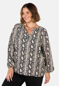 Blouse à manches longues en imprimé serpent beige et noir, avec un décolleté en V, une coupe ample et des manches resserrées. Tissu texturé avec un motif audacieux.