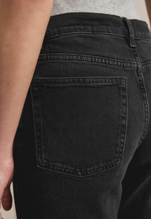 Fekete farmernadrág, amelyen egy hátul található zsebet finom hímzések díszítenek. A szövet sima tapintású, kiemelve a testhez simuló szabást.