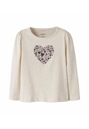 Chemise à manches longues de couleur crème avec épaules bouffantes et motif central en forme de cœur composé de petits cœurs violets et marron.