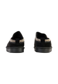 Paire de chaussures noires sans lacets avec bordure cousue beige et blanche, vue de dos sur fond blanc.