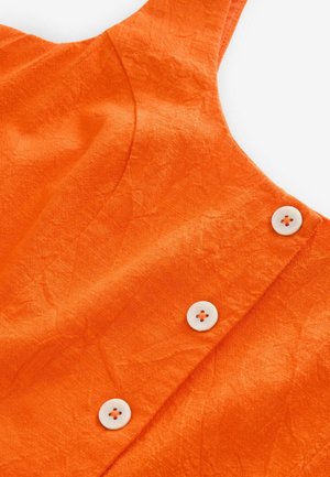 Tissu orange avec une texture froissée, featuring des boutons blancs sur le côté gauche et un design de décolleté incurvé.