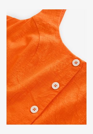 Tessuto arancione con una trama stropicciata, caratterizzato da bottoni bianchi sul lato sinistro e un design con scollatura curva.