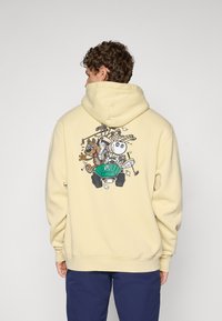 Yellow hoodie made of soft fabric, featuring a colorful cartoon design on the back with a green go-kart and playful characters.