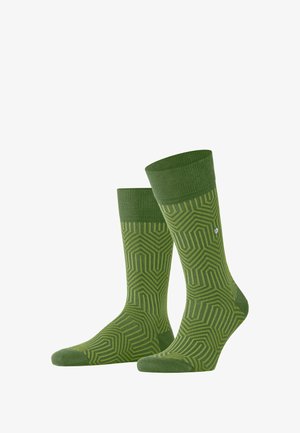 Grüne Socken mit einem geometrischen Muster, ausgestattet mit einem gerippten Bündchen. Hergestellt aus einem glatten Stoff mit unterschiedlichen Grüntönen.