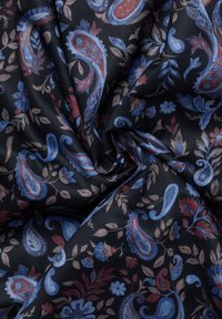 Zwarte stof met blauwe en rode paisley- en bloemmotieven, weergegeven met een gedraaide plooival in het midden.