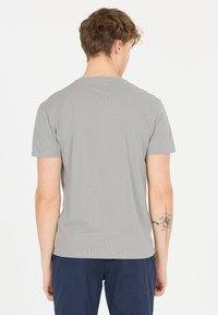 Gr�å bomulds t-shirt med korte ærmer, rund halsudskæring og glat tekstur. Synlig tatovering på venstre underarm, almindelig bagudsigt.