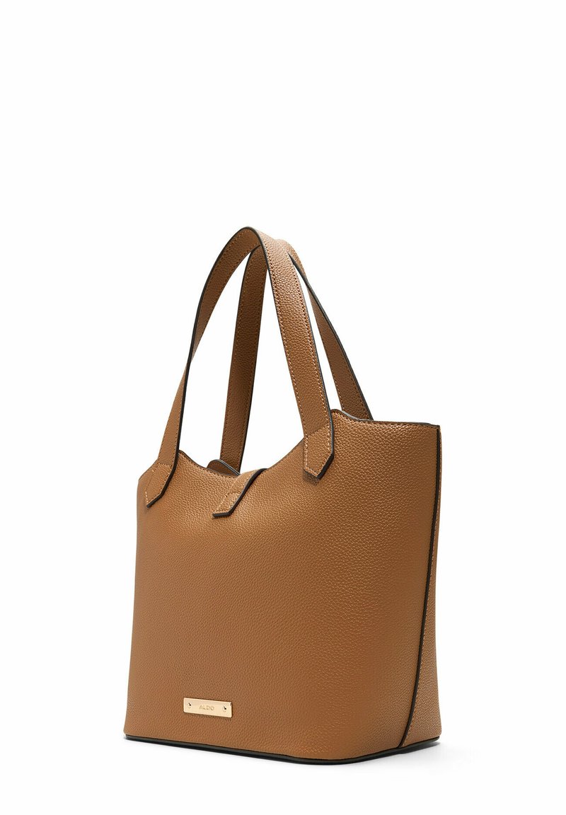 Sac fourre-tout en cuir marron avec surface texturée, bord noir et deux poignées robustes. Comprend une plaque de logo dorée à l'avant.