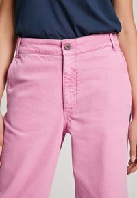 Calças de algodão cor-de-rosa claro com fecho de botão, apresentando uma textura suave e corte reto. Não há bolsos visíveis.
