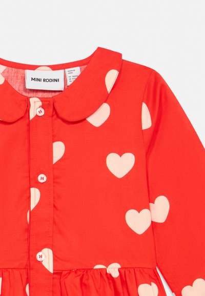 Raudona su baltais širdelių raštais ilgomis rankovėmis suknelė, Peterio Pano apykaklė, priekyje sagelės, su suveržtumu juosmens srityje, žymima Mini Rodini.
