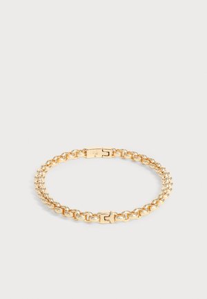 Bracelet chaîne ton or avec des maillons arrondis et un fermoir sécurisé, posé à plat sur un fond gris clair.