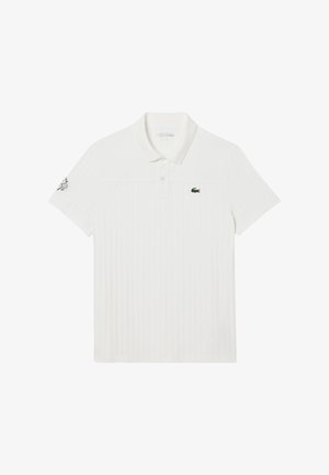 Witte polo shirt met korte mouwen en ribbeltextuur, met een knoopsluiting van twee knopen en een groen logo op de linkerborst. Heeft een ronde patch op de mouw.