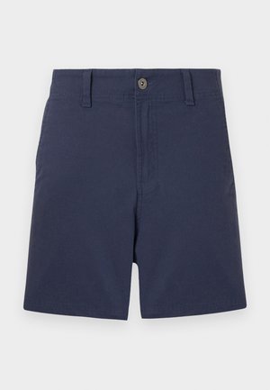 Σορτς για άντρες σε ναυτικό μπλε χρώμα με κούμπωμα με κουμπί, θηλιές για ζώνη και μπροστινές τσέπες, εμφανιζόμενο μπροστά σε απλό ανοιχτό χρώμα φόντου.