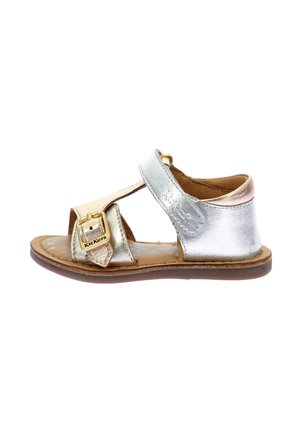 Sandalia metálica en plata y oro con hebilla, diseño recortado y suela marrón. Presenta tiras texturizadas y una plantilla acolchada.