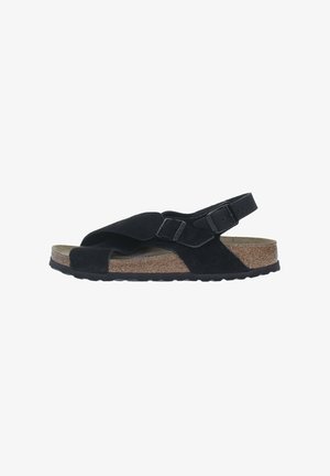 Sandali neri in suede con un design a fascia incrociata, cinturino regolabile sul tallone, sottopiede in sughero e suola in gomma texturizzata.