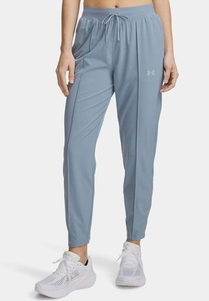 Pantaloni da jogging azzurri chiari con coulisse e tasche laterali, indossati con scarpe sportive bianche da una persona in piedi.