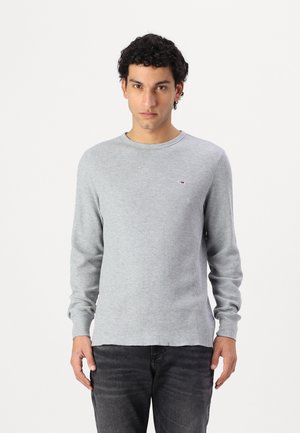 Grijze geribde lange mouw shirt gemaakt van een katoenmix, met een ronde hals en een klein logo op de borst. Draag het met donkere spijkerbroek.