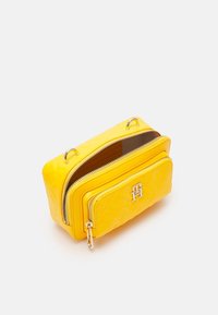 Borsa rettangolare gialla realizzata in materiale lucido, con due scomparti con zip, hardware argentato e un dettaglio con logo sulla parte frontale.