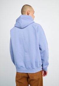 Sweatshirt à capuche bleu clair avec une coupe décontractée, fabriqué en tissu doux. Présente des poignets et un ourlet côtelés, avec des coutures minimales pour un look épuré.