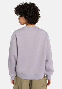 Sudadera lavanda con cuello redondo, hombros caídos y puños y dobladillo de canalé. Fabricada en un tejido suave con una textura lisa.