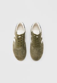 Αθλητικά παπούτσια από σουέντ σε ελιά πράσινο με λευκές λεπτομέρειες, κορδόνια, στρογγυλεμένη μύτη και επενδεδυμένο γιακά· με υφή στην επιφάνεια.