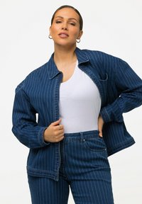 Jeansjacka med vertikala vita ränder, avslappnad passform, krage, dragkedja i fram, kombinerad med matchande högmidjade jeans. Avslappnad stil.