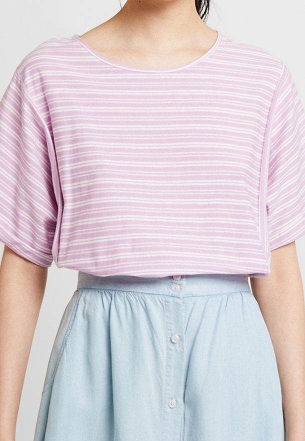 Ljuslila randig topp med korta dolmansärmar, rund halsringning och avslappnad passform. Matchas med en ljusblå skjortkjol.