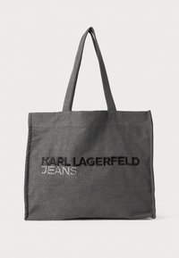 Grå tote-bag laget av stoff, med svart brodert tekst "KARL LAGERFELD" og "JEANS" med rhinestones. To skulderstropper.