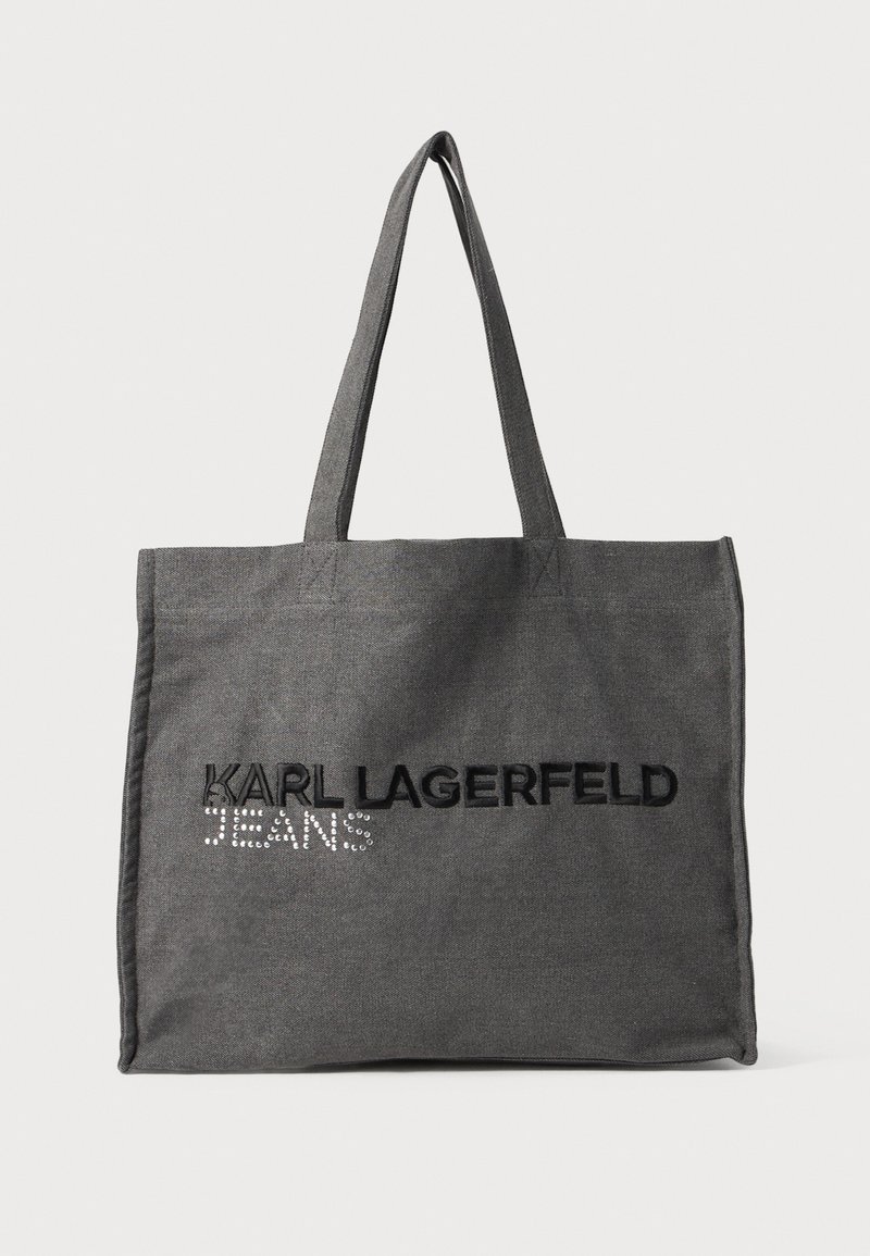 Grå tote-bag laget av stoff, med svart brodert tekst "KARL LAGERFELD" og "JEANS" med rhinestones. To skulderstropper.