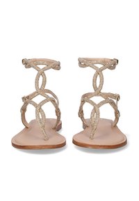 Sandalias planas doradas con intrincados detalles de cuentas y correas entrelazadas. Plantilla suave beige y fina correa en el tobillo con cierre de hebilla.