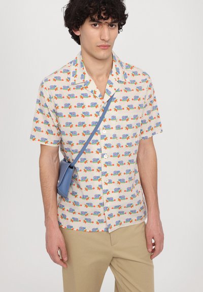 Chemise à manches courtes avec boutons en crème, ornée d'un motif de voitures colorées et de fleurs. À associer avec un pantalon beige clair et un sac bandoulière bleu.