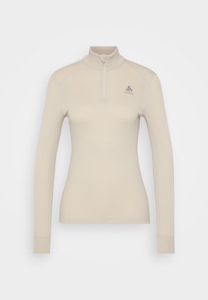 Lichtbeige langmouwen top met een hoge kraag en halve rits. Heeft een gladde textuur en een geborduurd logo op de linkerborst.